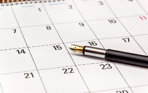 Image shows paper calendar with pen lying on it.