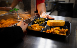 Image shows student receiving lunch tray in cafeteria.