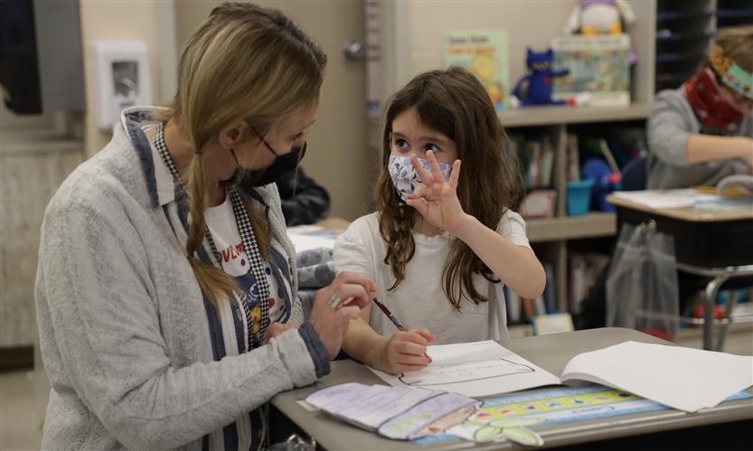 Teacher helps student at desk