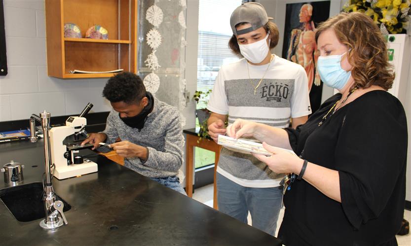 Teacher works with students in science lab