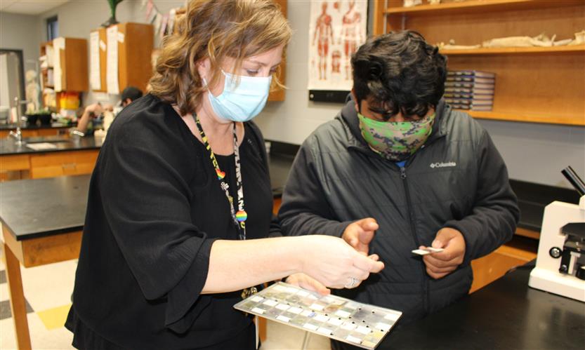 Teacher helps student in science lab
