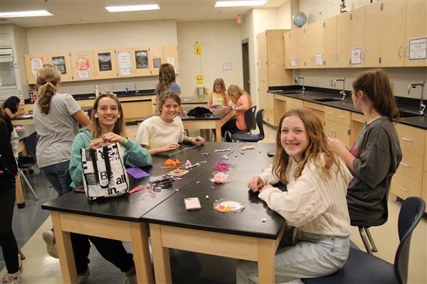 A group of seated female students work on arts and crafts.