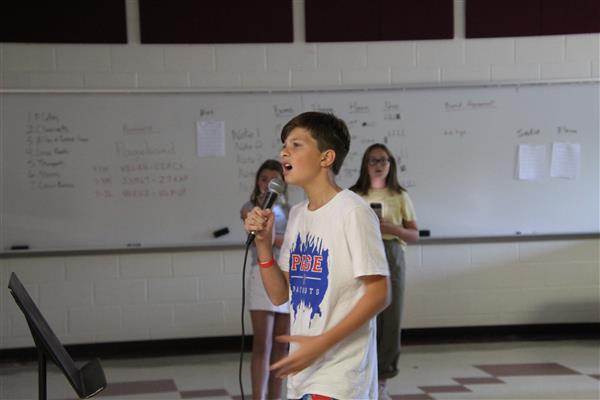 A male student sings into a microphone.