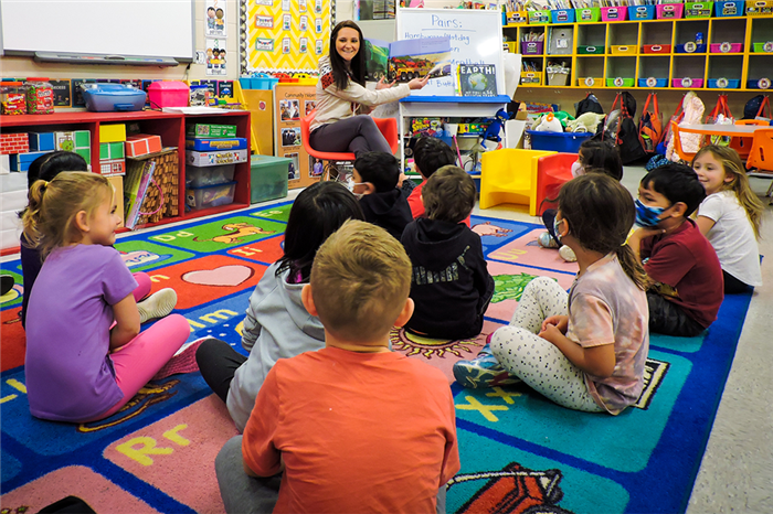 Teacher in her chairs and students on the carpet listening