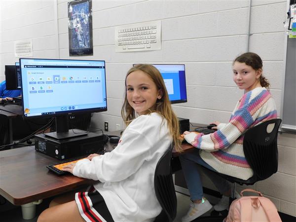 Two female WMS students are shown sitting at computers