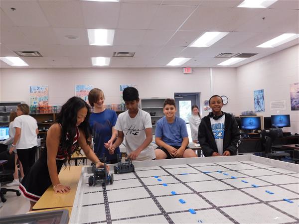 VEX Robotics students are shown with the BOTS at the competition table