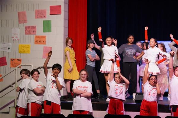 Student cast is shown on stage during a production
